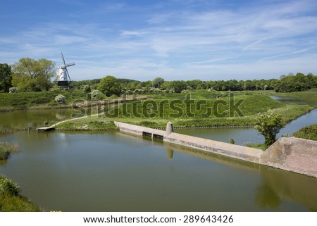 Typical Dutch countryside landscape with a canal, fortified wall and a windmill