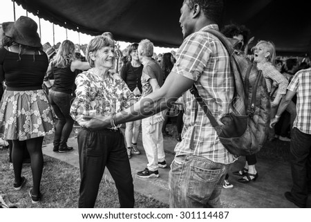 Amsterdam, The Netherlands - July 5 2015: young black man dancing salsa with old white lady during the concert of Colombian band LA-33 at cultural festival Amsterdam Roots Open Air in Park Frankendael