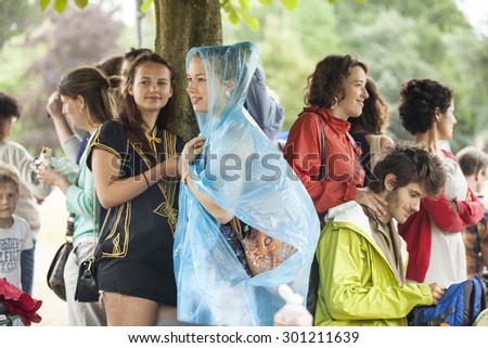 Amsterdam, The Netherlands - July, 5 2015: people taking shelter from the rain under a tree during Amsterdam Roots Open Air, a cultural festival held in Park Frankendael on 05/07/2015