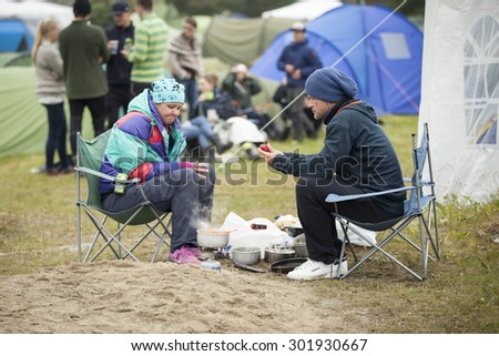 Traena, Norway - July 10 2015: man and woman cooking their diner at the campsite of Traenafestival, music festival taking place on the small island of Traena