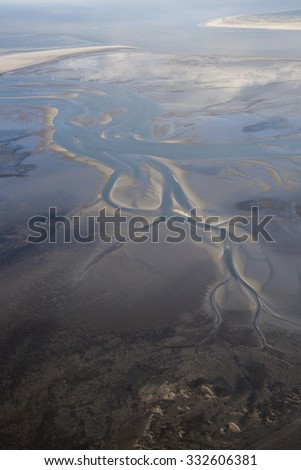aerial view of the mudflat coastline at low tide with water winding in the mud and sand bank, Frisian island Ameland, The Netherlands
