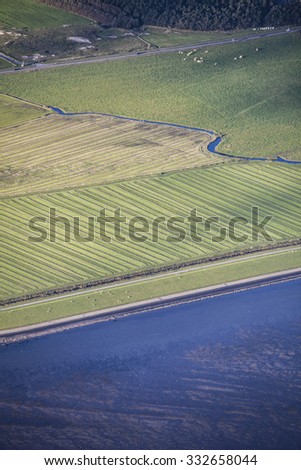 Aerial coastal view of the shore of Ameland Frisian Island with green fields, dike and sea, The Netherlands