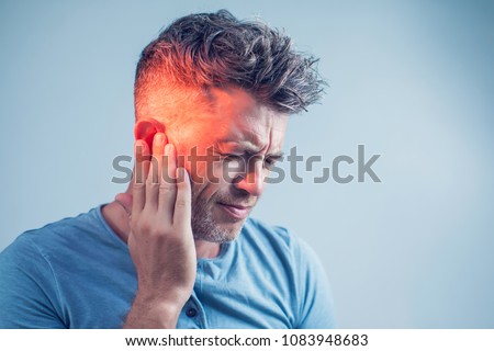 male having ear pain touching his painful head isolated on gray background