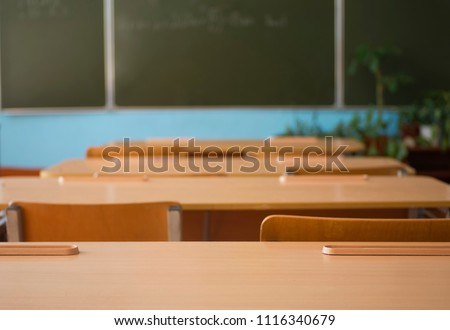 School classroom with school desks and blackboard in high school. Empty classroom background.