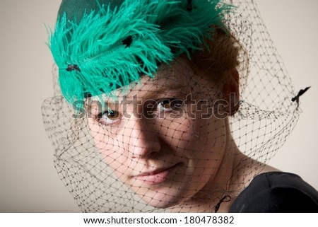 Redhead in a green veiled hat with feather