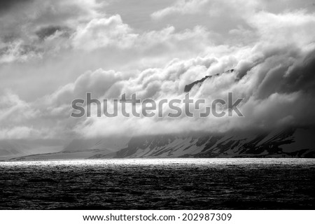 Black and white cliff beside backlit ocean