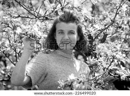 KROSNO,POLAND - CIRCA 1948: vintage photo of young woman and blossoming apple tree
