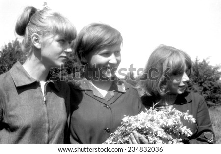 JASLO,POLAND - CIRCA 1965 : vintage photo of three girls outdoor with flowers