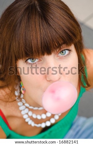 Young girl blowing pink chewing gum bubble