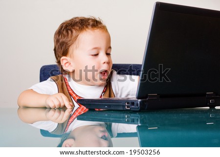 Small boy sitting at the table with laptop