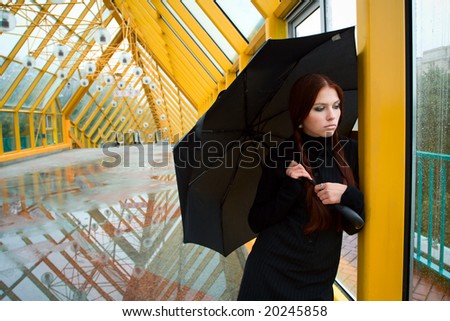 Pretty sad girl with umbrella by the window