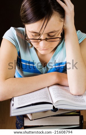 Young girl in glasses is reading a big book