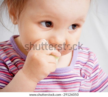 Small girl biting a piece of food