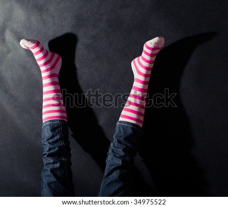 Woman legs in striped socks on dark background