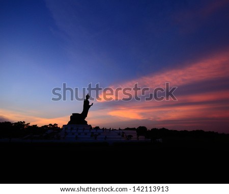 Silhouette Buddha with red clouds and blue sky