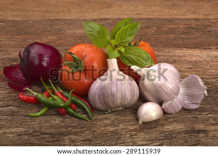 garlic tomato red onion chilli and basil leaves on rustic look timber blur background