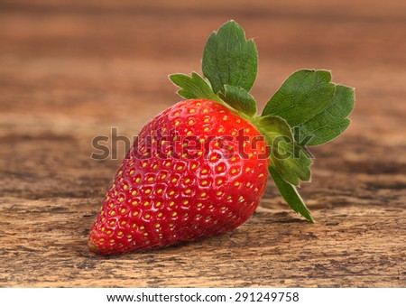 A single red ripe strawberries arranged on old rustic look timber with out of focus timber in the background