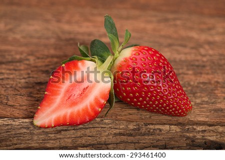 Fresh red ripe whole strawberry and a half on old rustic look timber