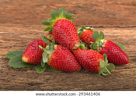 Fresh red ripe whole strawberries and leaves on old rustic look timber