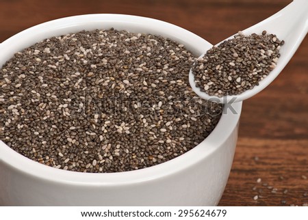 Dry chia seeds healthy super food in a white cup and in a white spoon place on old rustic look timber background