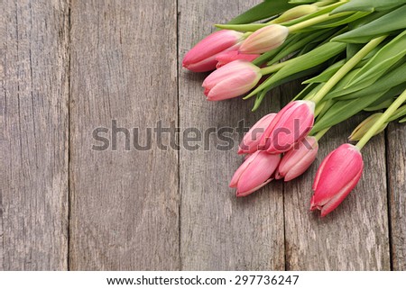 Beautiful pink tulip flowers and leaved place on old rustic look timber table