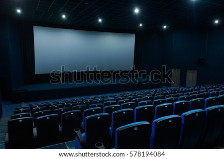 Empty blue cinema room with white screen and seats. Side view
