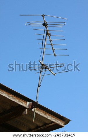 Old TV antenna on house roof with bule sky