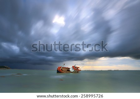 sinking boat with rain cloud moving sky in background