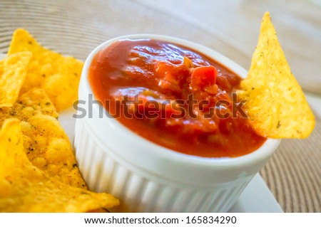 Spicy red salsa with a plate of tortilla chips, focus on the sal