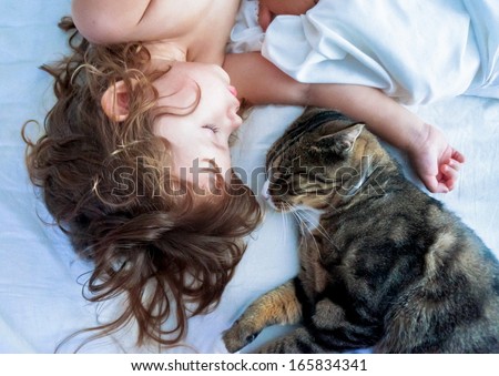 Young Girl And Kitten Sleeping On A White Bed Linen At Home