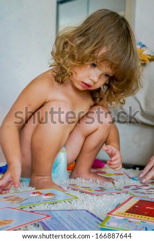 Cute baby is playing with educational cards