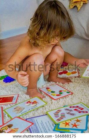 Cute baby is playing with educational cards