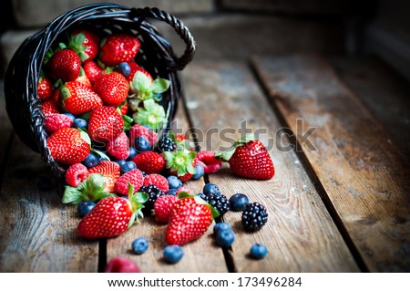 Mix Of Fresh Berries In A Basket On Rustic Wooden Background