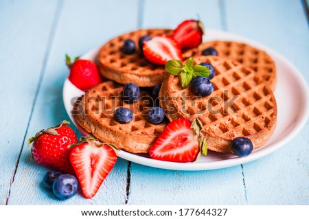 Whole grain waffles with berries on blue wooden background