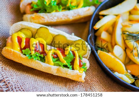 Hot Dogs with french fries in the skillet on wooden background