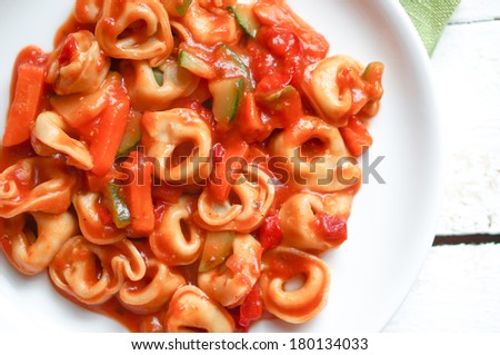Tortellini primavera parmesan in marinara sauce on wooden rustic background