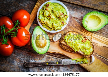Guacamole with bread and avocado on rustic wooden background