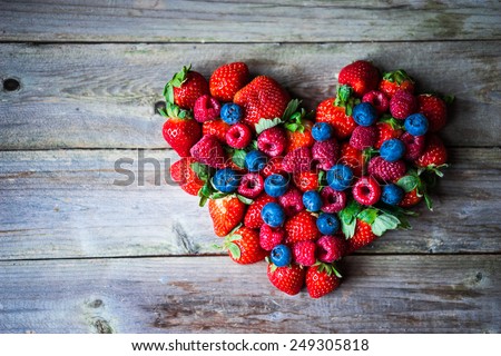 Heart of berries on wooden background