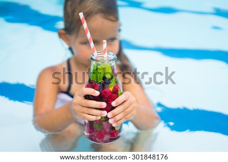Cute girl is drinking detox water in the pool