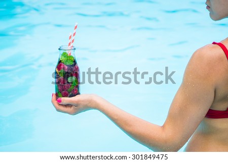 Woman in the pool with detox water cocktail