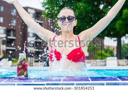 Woman in the pool with detox water cocktail