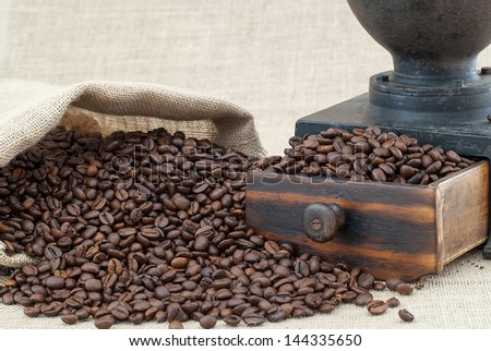 Burlap bag filled with coffee beans on burlap background