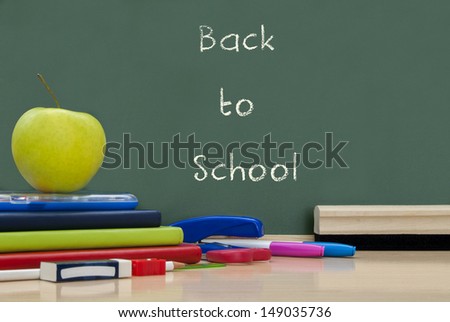 Back to school written on a blackboard with school supplies