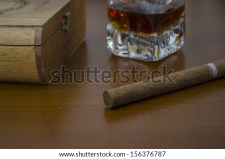a cigar Havano first term and the bottom a box of cigars and a glass of whiskey