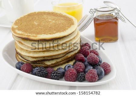A healthy breakfast with Homemade pancakes with  berries and  honey  orange juice and cup coffee