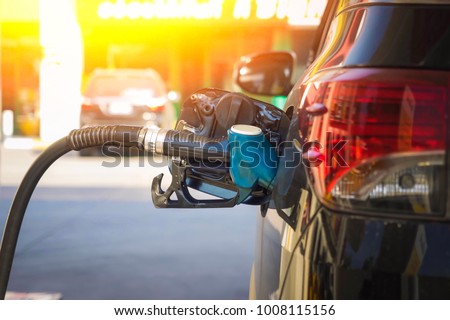 Refueling a petroleum vehicle at gas station in warm sunset