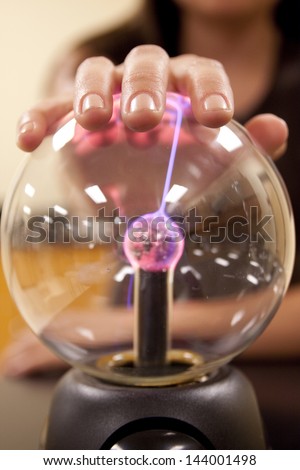 A female student investigates the properties of a plasma ball.