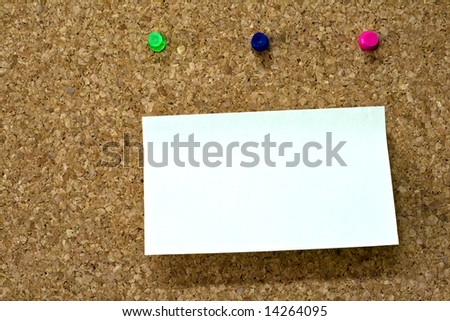 Blank reminder on wooden board and three colorful pins