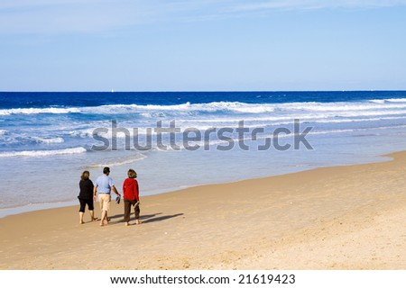 One man and two women taking a peaceful walk on the beach