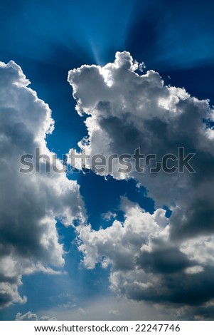 View of blue sky with sun rays through the clouds